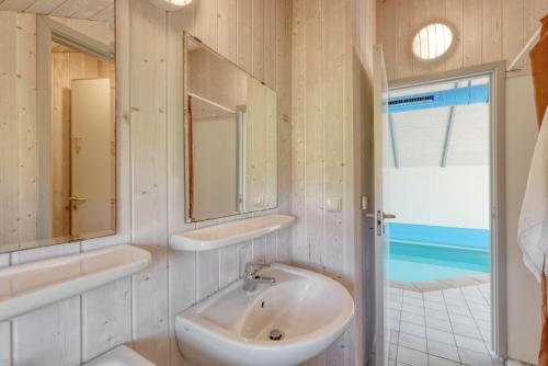 een badkamer met een wastafel en 2 spiegels bij Kranich Ferienhäuser mit Innenpool in Hohendorf