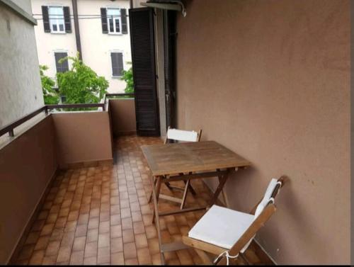 balcón con mesa de madera y 2 sillas blancas en Bergamo & Dintorni, en Bérgamo