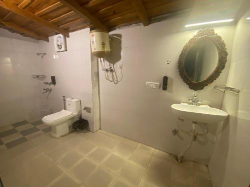 a bathroom with a toilet and a sink and a mirror at Wincliff Orchard Resort in Mukteswar
