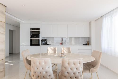 a white kitchen with a dining room table and chairs at Sunset Home, Appartement de luxe front de lac in Veytaux