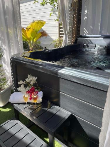 a hot tub with a table and two glasses of wine at OSun Bungalow in Saint-Leu