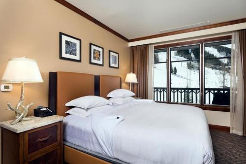 a bedroom with a large white bed and a window at Aspen Ritz-carlton 2 Bedroom Ski In, Ski Out Residence With Access To Slopeside Heated Pools And Hot Tubs in Aspen