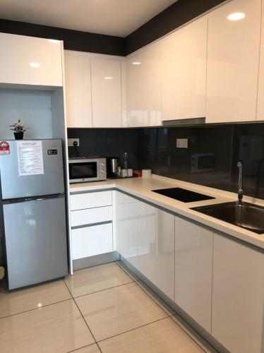 a kitchen with white cabinets and a stainless steel refrigerator at Almas Puteri Harbour Nusajaya Suite room Exclusive Room 5 min to Legoaland by HomeSpace in Nusajaya