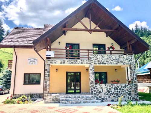 a house with a balcony on top of it at Pensiunea Bucur in Dămuc
