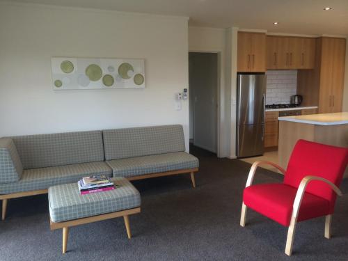 a living room with a couch and a red chair at Matagouri Cottage - Lake Tekapo in Lake Tekapo