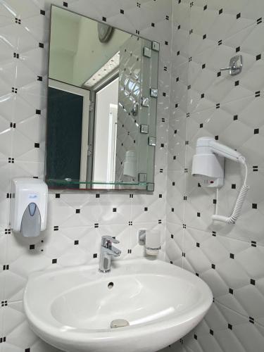 a white bathroom with a sink and a mirror at Villa Bodini Himare in Himare