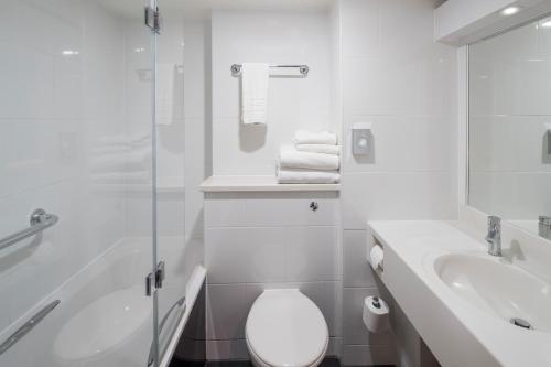 a white bathroom with a toilet and a sink at Crowne Plaza Plymouth by IHG in Plymouth