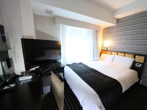 um quarto de hotel com uma cama e uma televisão de ecrã plano em APA Hotel Asakusabashi-Ekikita em Tóquio