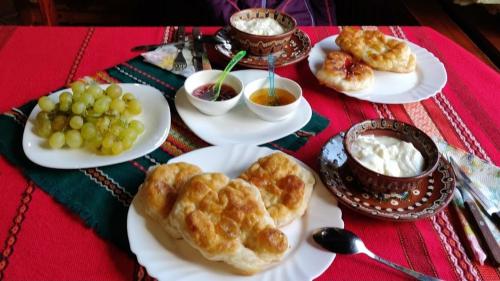 a table with plates of pastries and grapes and dip at Къща за гости Динас in Zmeitsa