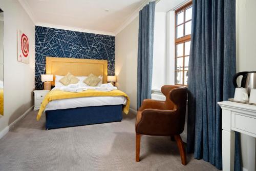 um quarto com uma cama e uma cadeira em The Victoria Hotel em Bamburgh