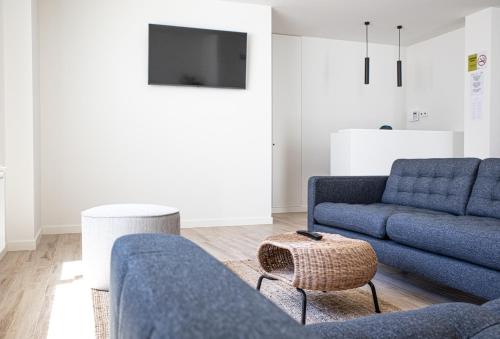 ein Wohnzimmer mit 2 blauen Sofas und einem TV in der Unterkunft Hostal Náutico de Razo in Carballo