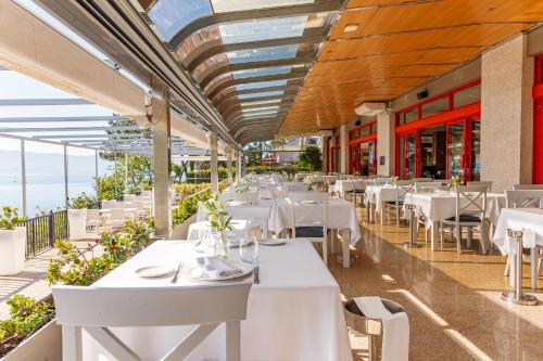 um restaurante com mesas e cadeiras brancas e o oceano em Gran Talaso Hotel Sanxenxo em Sanxenxo