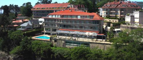 un edificio con techo rojo y piscina en Gran Talaso Hotel Sanxenxo, en Sanxenxo