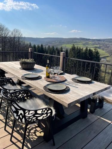 een houten tafel op een terras met stoelen en een tafel bij Suites de la vallée 6 in Érezée