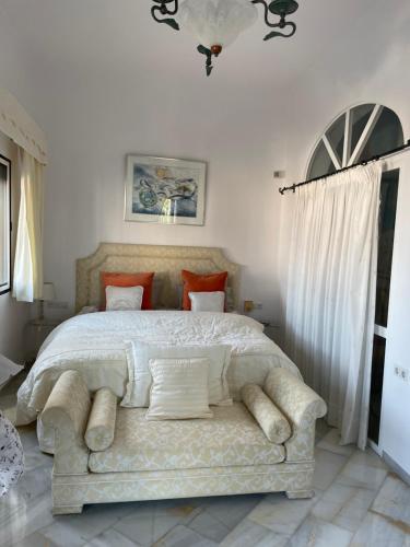 1 dormitorio con 1 cama grande con colcha blanca y sofá en Villa Ladera Panorama - private heated pool, en Nerja