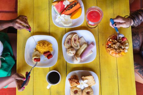 een houten tafel met borden met eten erop bij Pousada Vila Bacana in São Miguel do Gostoso
