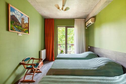 two beds in a room with a chair and a window at Veli group Apartment near White Bridge ° in Kutaisi