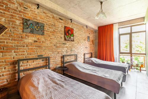 two beds in a room with a brick wall at Veli group Apartment near White Bridge ° in Kutaisi