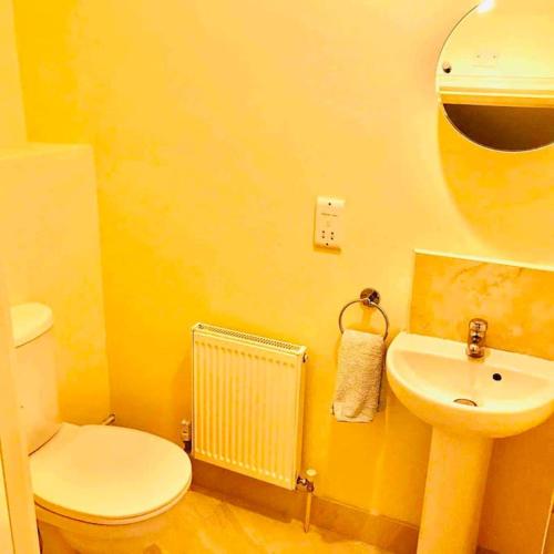 a yellow bathroom with a toilet and a sink at Semi-detached Armagh House in Armagh