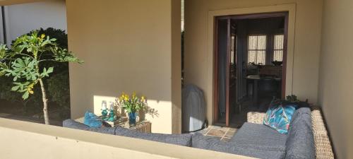 a balcony with a blue couch on a building at Plettenberg Bay Unit 10 Whale Rock Gardens Apartment in Plettenberg Bay