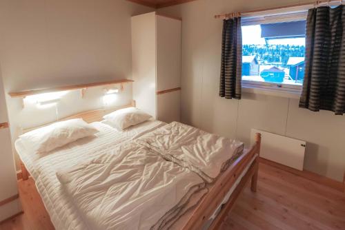 a bedroom with a large white bed with a window at Fagertoppen 12B in Trysil