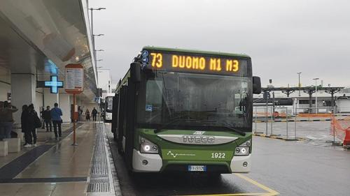 a green bus is parked at a bus stop at Appartamento DeLuxe con parcheggio gratuito in Segrate
