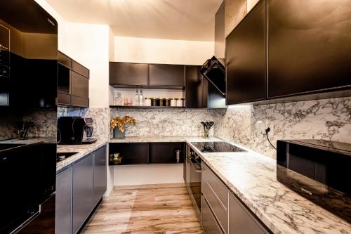 a kitchen with black cabinets and marble counter tops at Apartmán Sabína in Liptovský Mikuláš