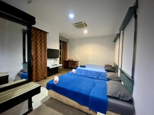 a bedroom with a blue bed and a television at KB MYPLACE in Kota Bharu