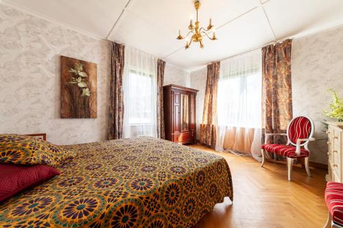 a bedroom with a bed and a chair and windows at Old villa Kaprice Baltic Beach in Jūrmala