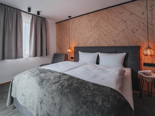 a bedroom with a large bed with a wooden wall at ARLhome - Zuhause am Arlberg in Sankt Anton am Arlberg