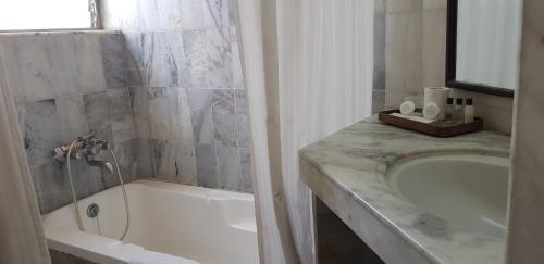 a bathroom with a bath tub and a sink at The Meadows Resort and Spa in Aurangabad