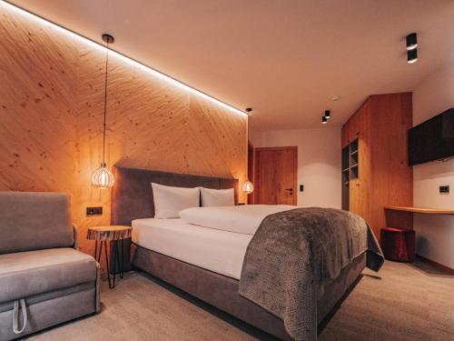 una camera con un grande letto e una sedia di ARLhome - Zuhause am Arlberg a Sankt Anton am Arlberg