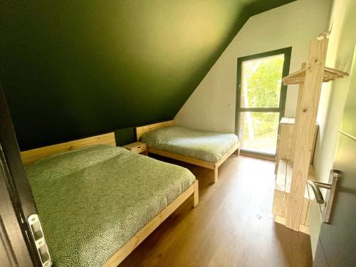 een groene kamer met 2 bedden en een raam bij L’Éterle, maison de montagne in Aucun