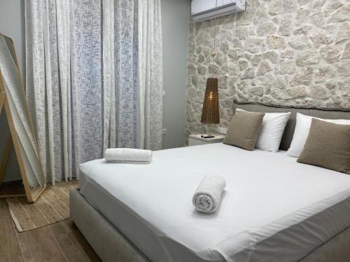 sypialnia z dużym białym łóżkiem i kamienną ścianą w obiekcie Villa Massari w mieście Charaki