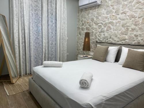 a bedroom with a large white bed with a stone wall at Villa Massari in Haraki