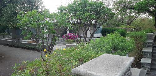 a bench in a garden with trees and flowers at The Meadows Resort and Spa in Aurangabad