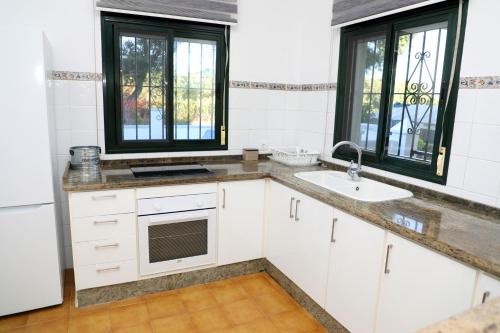 uma cozinha com armários brancos, um lavatório e janelas em Casa La Herradura 2 em Vejer de la Frontera