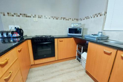 a kitchen with a stove and a microwave at First Group Brookes Hill Suites in Summerstrand