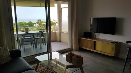 Il comprend un salon avec un canapé, une télévision et un balcon. dans l'établissement Nice: Bel Appartement Vue Mer avec Grande Terrasse, à Nice