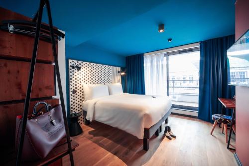 a bedroom with a white bed and a large window at BOMA easy living hotel in Strasbourg