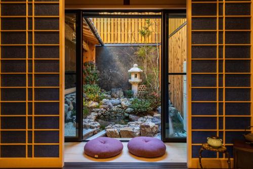 Habitación con 2 almohadas moradas en el suelo, junto a un jardín. en 京恋 黄金屋 en Kyoto