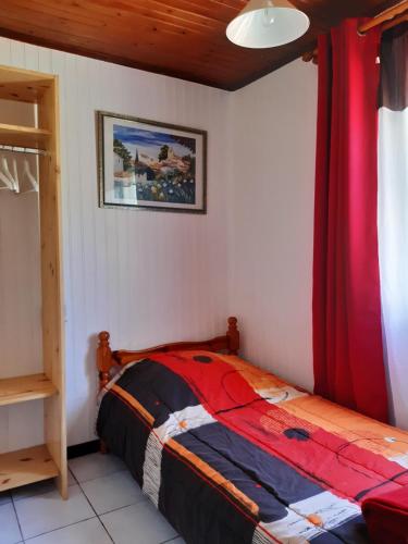 1 dormitorio con 1 cama con cortina roja en Les Lierrres, en Cilaos