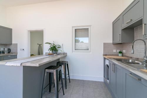 a kitchen with gray cabinets and bar stools at Archers House in Stevenage