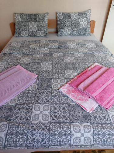 a bed with two pillows and pink sheets on it at Ino 99 in Užice