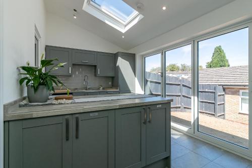 a kitchen with green cabinets and a large window at Archers Lodge in Stevenage