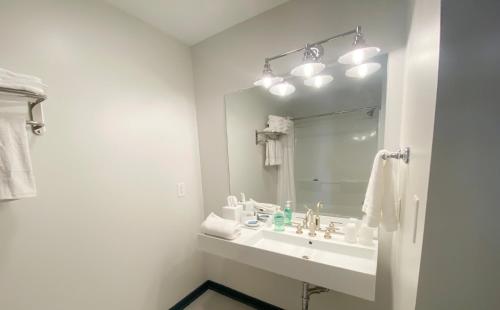 ein weißes Badezimmer mit einem Waschbecken und einem Spiegel in der Unterkunft Rivers Rest Resort 