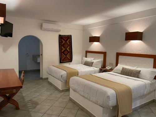 a hotel room with two beds and a desk at Aldea del Bazar in Tehuacán