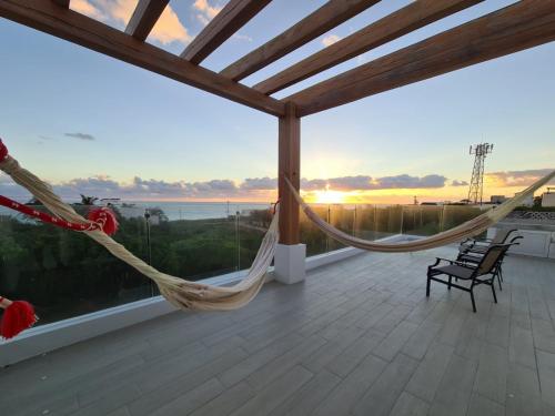 a hammock on a patio with a view of the ocean at Luxury Villa Cascada- infinity oceanview pool and elevator in Isla Mujeres