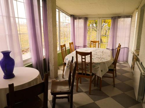 - une salle à manger avec une table, des chaises et des fenêtres dans l'établissement Agradable casa con jardín: Casasola, à San Cristóbal de Segovia