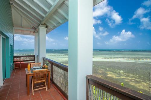 a balcony with a table and chairs and the ocean at Les Villas du Lagon in Le François